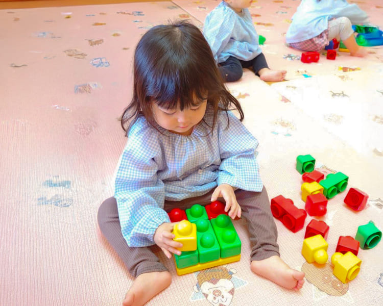 知育玩具のブロックを使って集中して遊ぶ園児