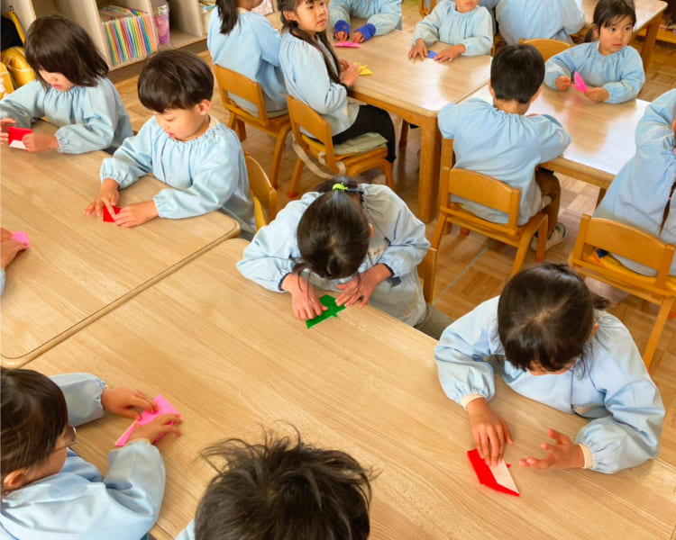 教室でみんなと一緒に集中して折り紙を折る様子