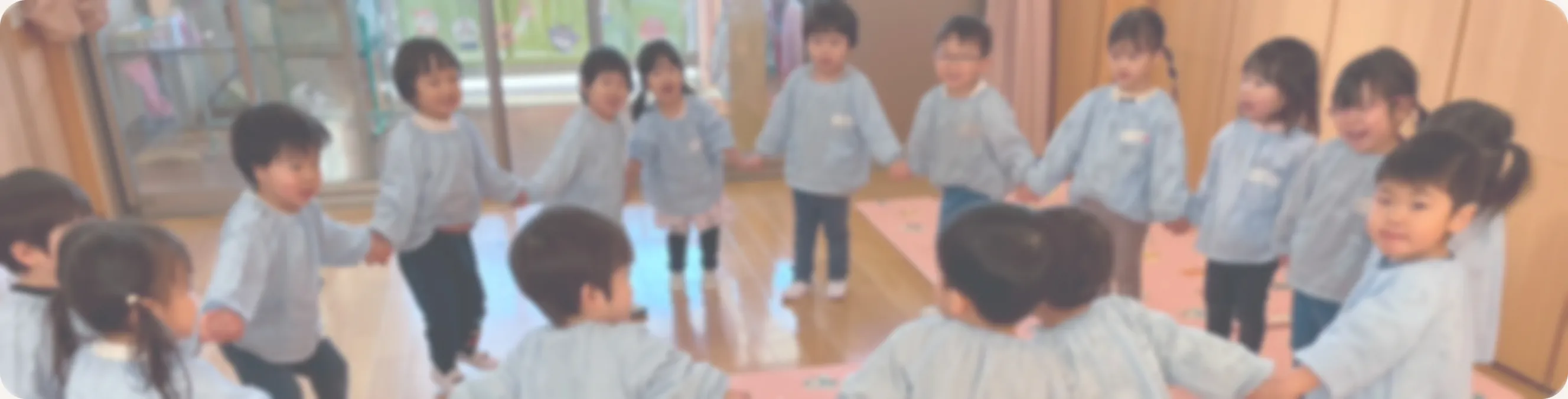 0〜2歳児の乳児クラスで、お友達や先生と一緒に手をつないで遊ぶ様子