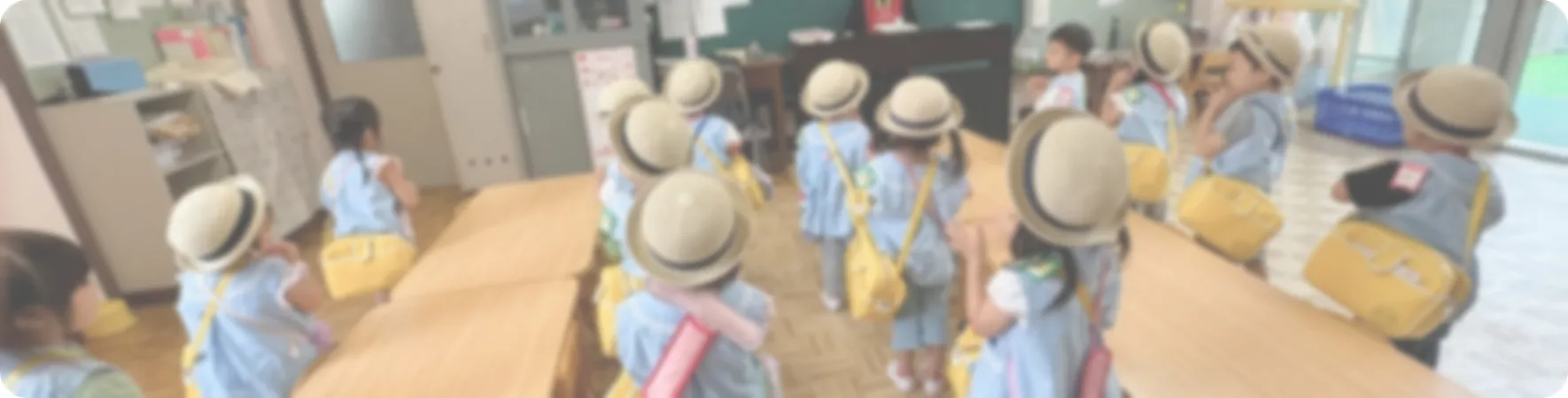3〜5歳児の幼児クラスで、お揃いの通園帽子とカバンを身につけ、お出かけの準備をする園児たち