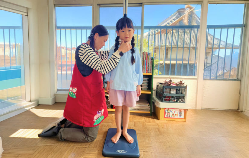 先生に身長や体重を測ってもらい、成長を確認する身体測定の様子