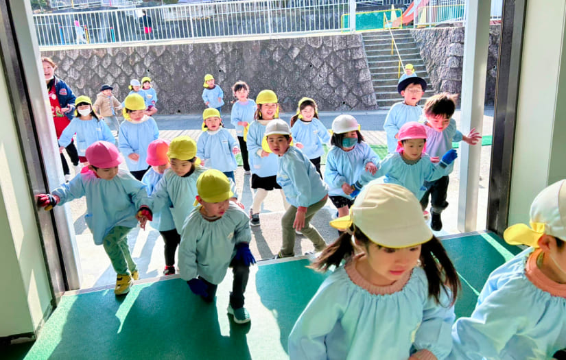園児が先生の指示に従って安全に園庭へ避難する訓練の様子