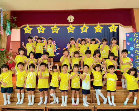 おそろいの黄色のTシャツを着て集合写真をとる七夕まつりの様子