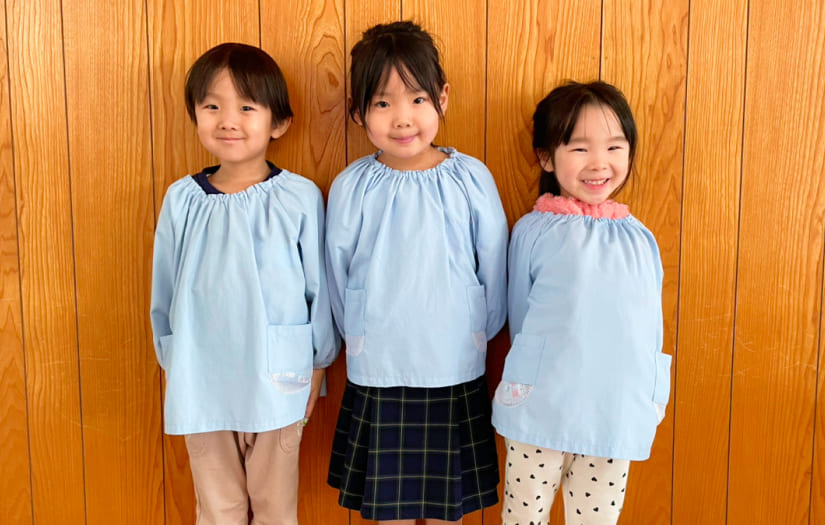 年長・年中・年少の園児が活動中に着用する水色のスモック