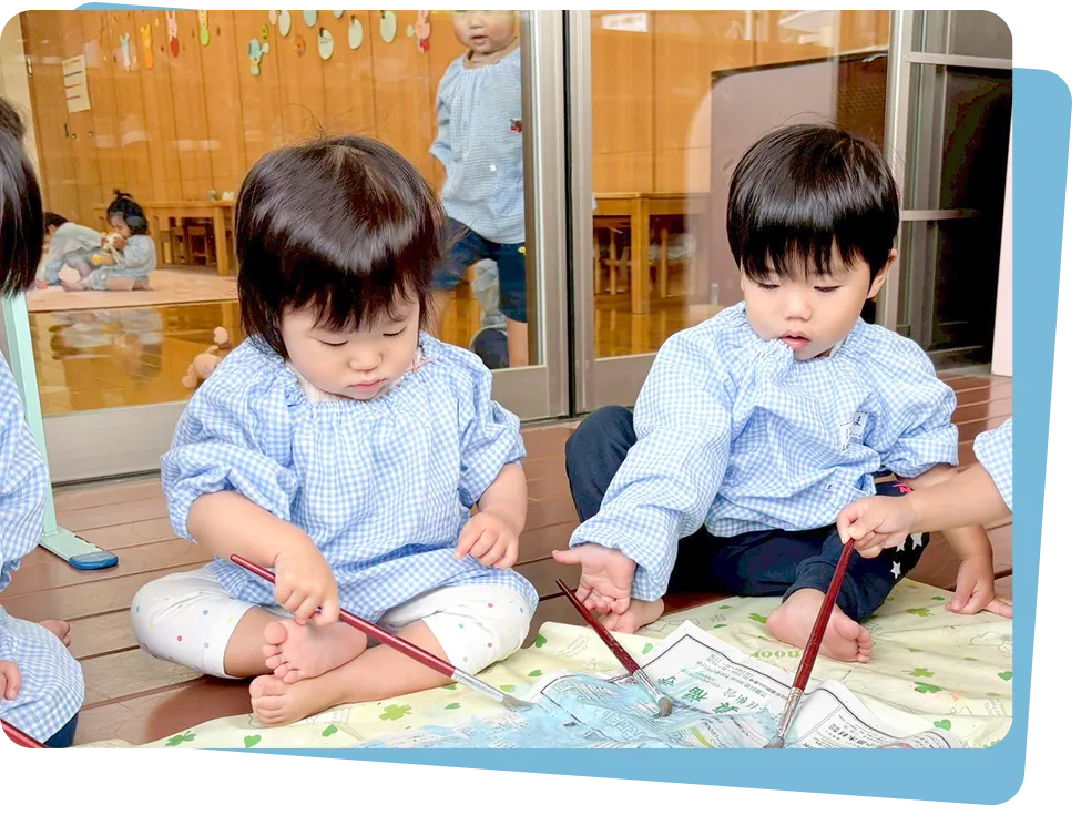 テラスで筆を使い、のびのびとお絵描きを楽しむ小さな園児たち