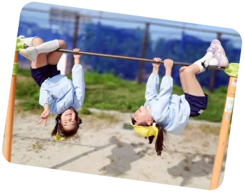 園庭の鉄棒にぶら下がって笑顔でポーズをとる園児たち