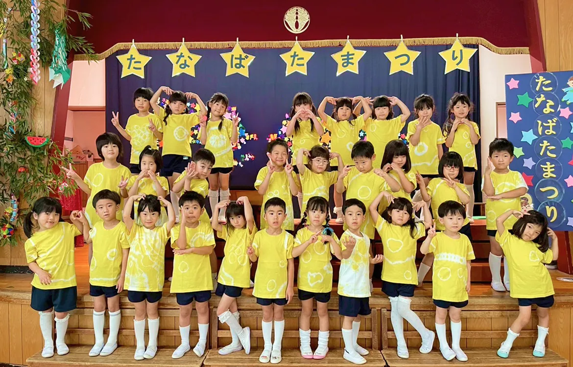 たなばたまつりのステージで自分で作った有松絞Tシャツを着てポーズをとる園児たち